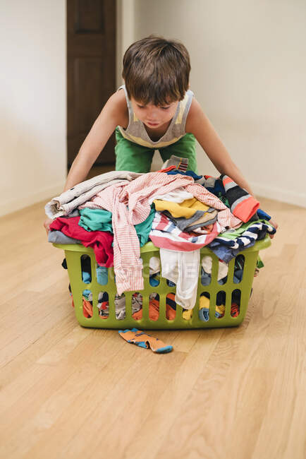 Kleiner Junge trägt sehr vollen Wäschekorb — Stockfoto