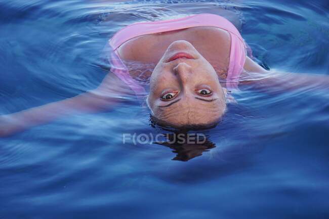 Молода жінка плаває на спині у басейні — стокове фото