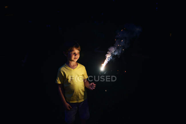 Junge steht draußen mit Wunderkerze — Stockfoto