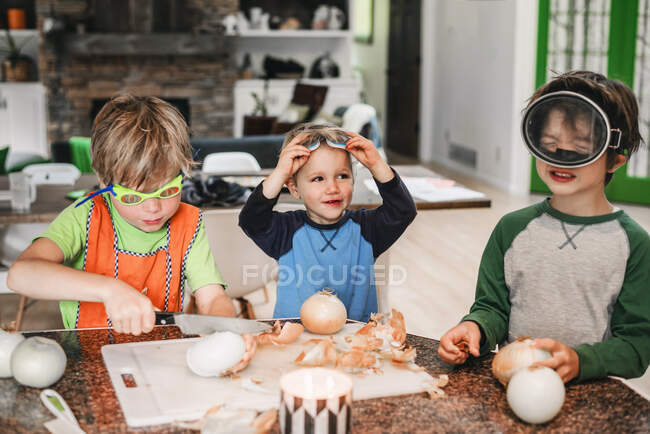 Tres niños pequeños ayudando a cocinar en la cocina - foto de stock