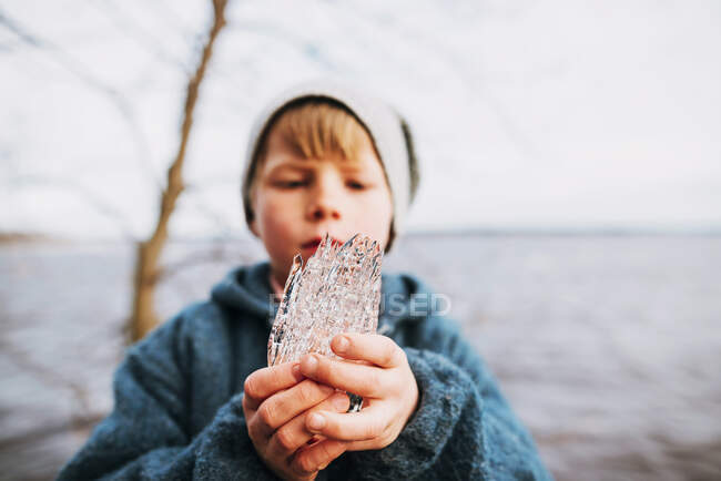 Young boy holding chunk of ice on nature — Stock Photo