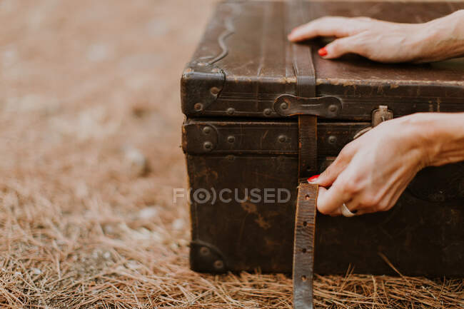 Plan recadré de femme avec de vieux bagages en bois — Photo de stock