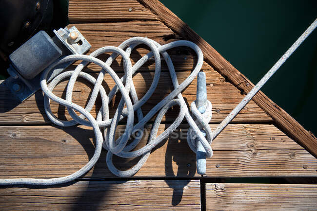 A white rope lies on an old weathered dock along the bay — Stock Photo