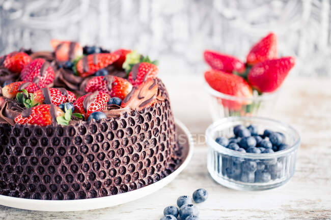 Schokoladenkuchen mit frischen Erdbeeren und Blaubeeren auf einem Holztisch — Stockfoto