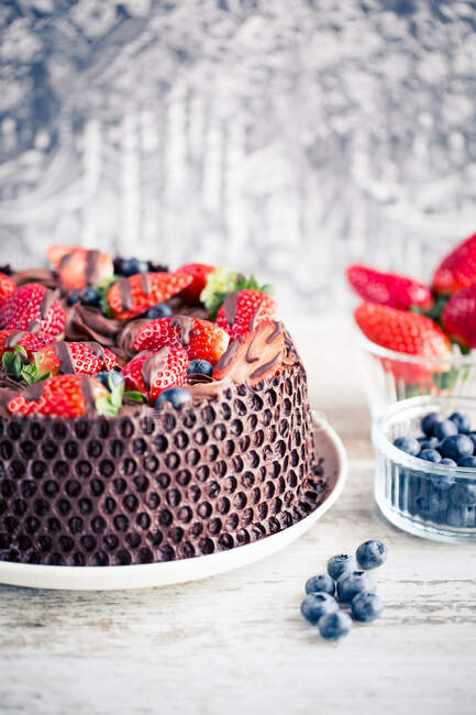 Schokoladenkuchen mit frischen Erdbeeren und Blaubeeren auf einem Holztisch — Stockfoto