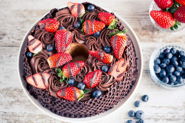 Шоколадный торт со свежей клубникой и черникой на деревянном столе — стоковое фото