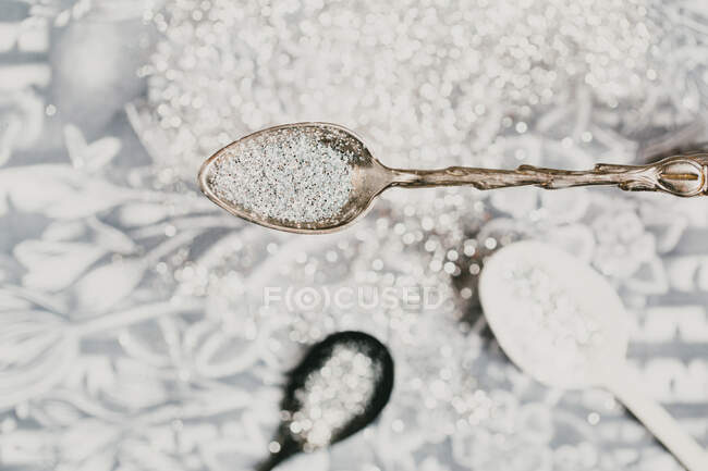 Spoon of glitter over shiny decorated background — Stock Photo