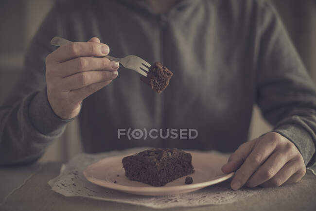 Hombre sosteniendo pedazo de pastel de chocolate en tenedor - foto de stock