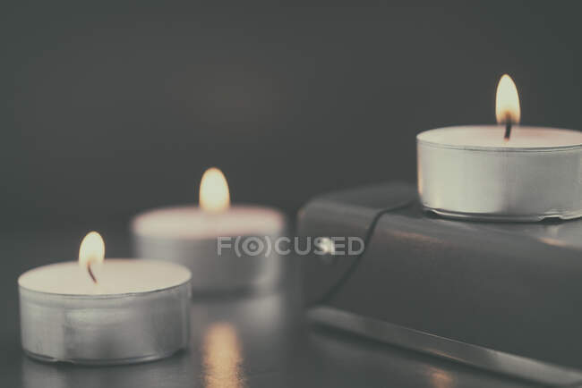Burning candles on table and on book, closeup — Stock Photo
