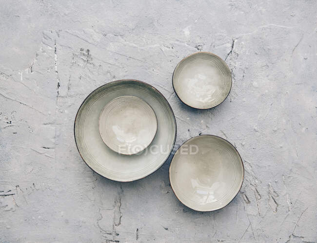 Vista superior de tigelas de cerâmica branca com placa vazia sobre fundo cinza — Fotografia de Stock