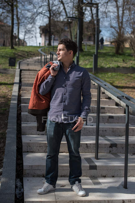 Мужчина, стоящий на ступеньках с курткой через плечо — стоковое фото