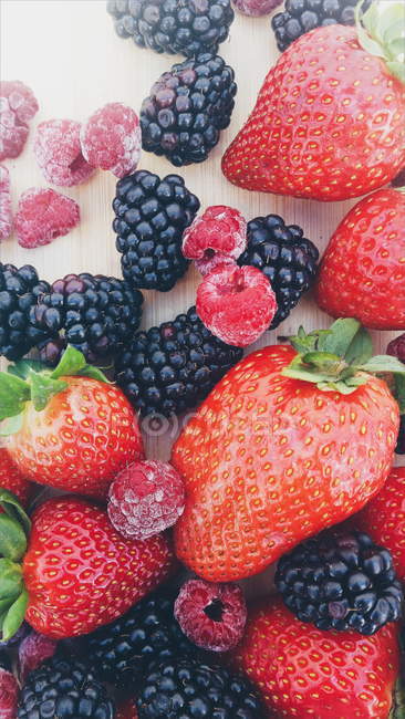 Strawberries, blackberries and raspberries on a chopping board — Stock Photo
