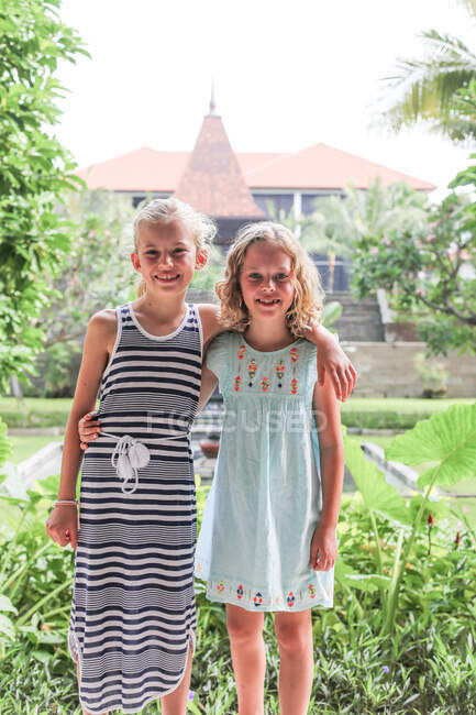 Retrato de dos niñas con el brazo alrededor unas de otras delante de un templo, Ubud, Bali, Indonesia - foto de stock