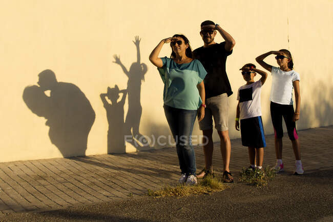 Семья, стоящая у стены и делающая тени — стоковое фото