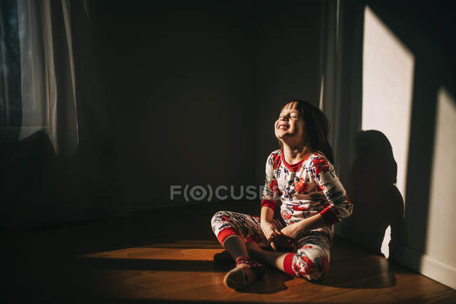 Дівчина сидить на підлозі в її піжамах сміється — стокове фото