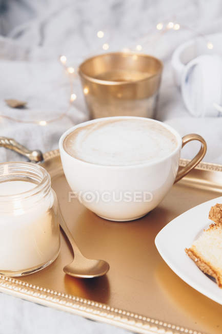 Cup of coffee on gold tray with a candle — Stock Photo