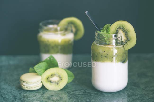 Dos ollas de yogur natural con kiwi y menta fresca - foto de stock