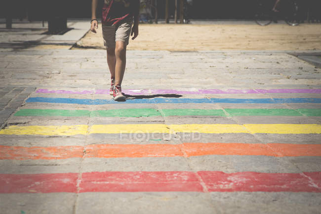 Menino cruzando uma travessia de pedestre arco-íris — Fotografia de Stock