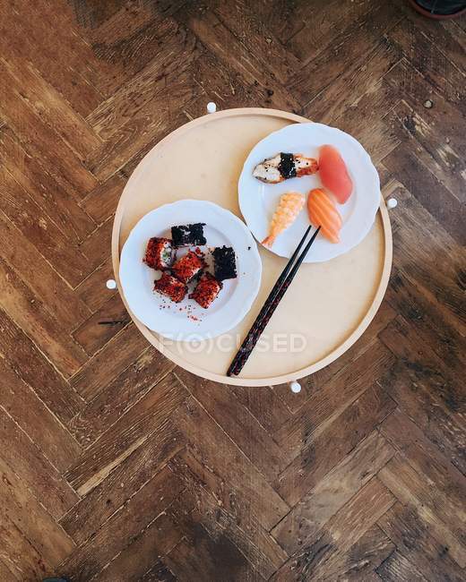Blick von oben auf schmackhaftes Sushi auf Teller, Holzhintergrund — Stockfoto