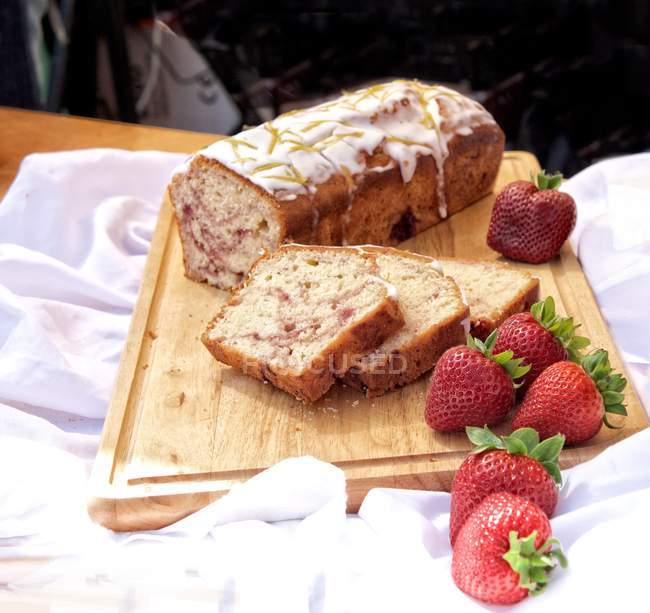 Fruit bread loaf with strawberries on chopping board — Stock Photo