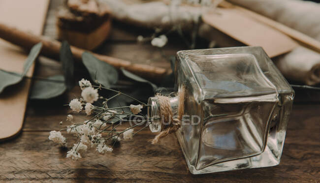 Скляна пляшка і квітка лежать на столі — стокове фото