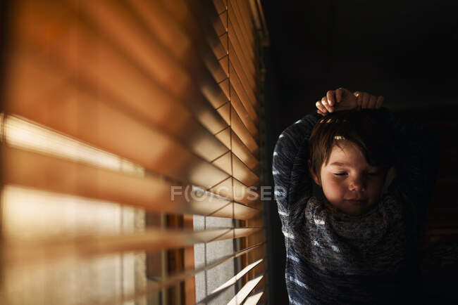 Cansado menino de pé por uma janela de alongamento — Fotografia de Stock