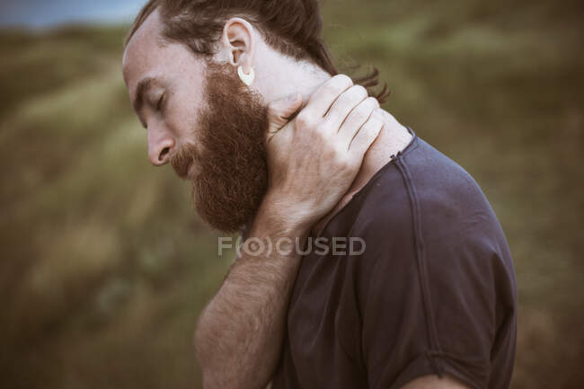 Retrato de um homem bonito segurando seu pescoço — Fotografia de Stock