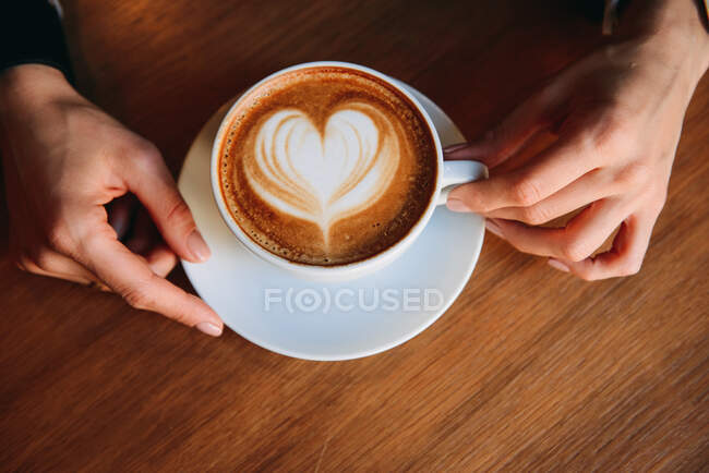 Woman's hand holding a cappuccino — Stock Photo