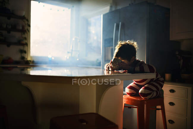 Ragazzo seduto in cucina a mangiare la sua colazione in luce del mattino — Foto stock