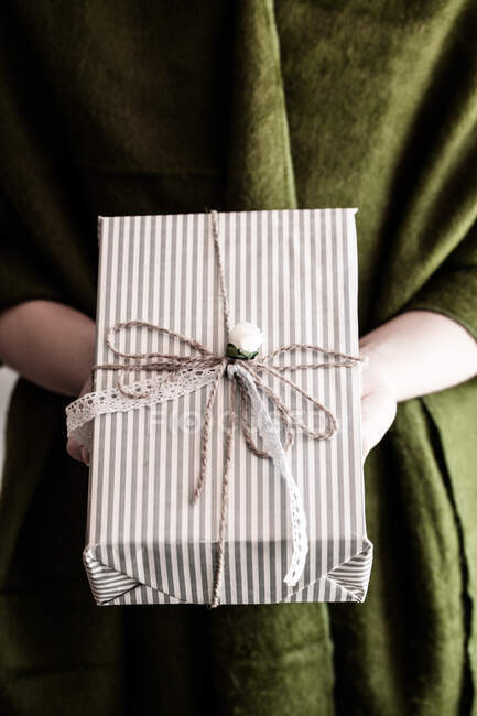 Main de fille tenant un cadeau enveloppé — Photo de stock