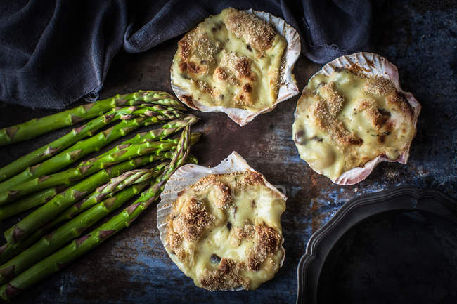 Mussel gratin in scallop shells with fresh asparagus — Stock Photo