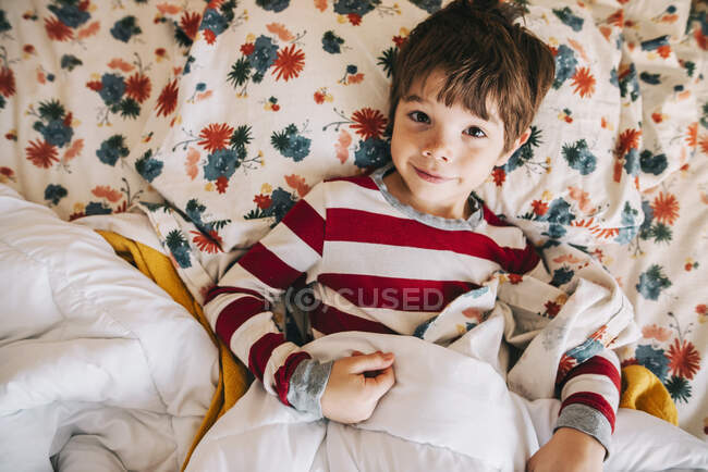 Крупним планом портрет усміхненого хлопчика, що лежить у ліжку — стокове фото
