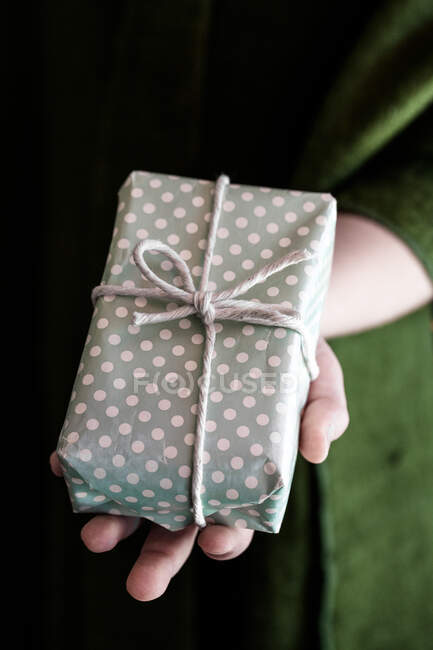 Mano de niña sosteniendo un regalo envuelto — Stock Photo