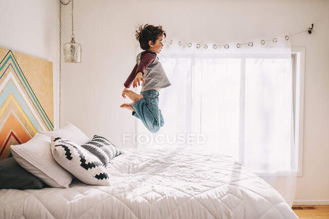 Porträt eines Jungen, der auf ein Bett springt — Stockfoto