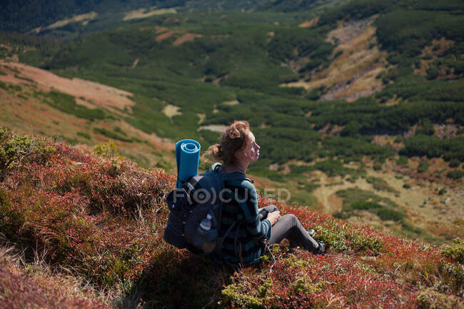 Donna seduta sul pendio della montagna guardando la vista, Ucraina — Foto stock