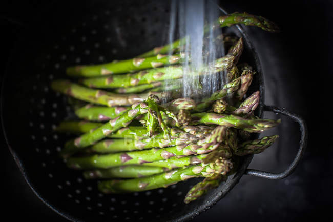 Closeup view of Asparagus in a colander being washed — Stock Photo