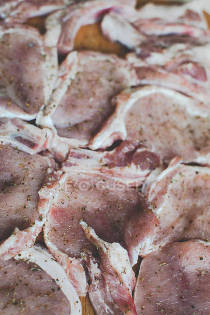 Bistecche di maiale crude con spezie su un tagliere — Foto stock