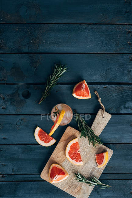 Paloma cocktail with grapefruit slices and rosemary on a chopping board — Stock Photo