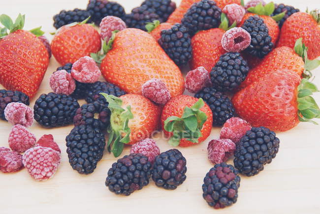 Strawberries, blackberries and raspberries on a chopping board — Stock Photo