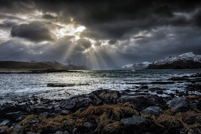 Lumière du soleil à travers les nuages dans un ciel lunaire, Nordland, Lofoten, Norvège — Photo de stock