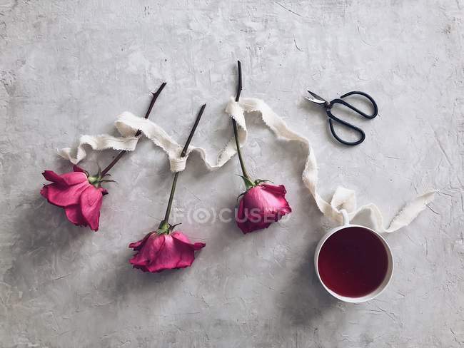 Tres rosas y una taza de té a base de plantas - foto de stock