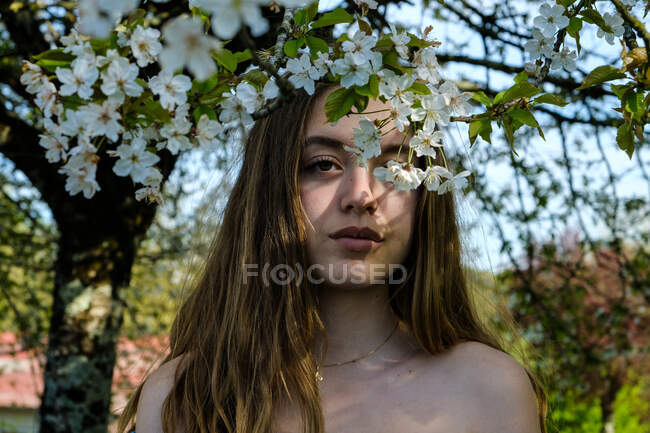 Портрет девочки-подростка, стоящей под цветущей вишней — стоковое фото