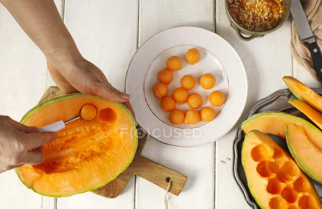 Mains de femme coupant un melon frais, vue de dessus — Photo de stock
