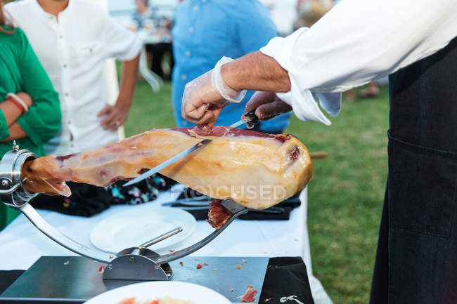 Homme tranchant un jamon iberico de bellota — Photo de stock