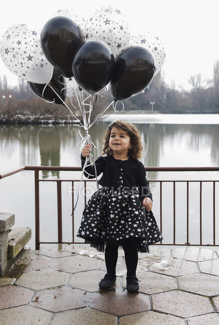 Menina feliz segurando um monte de balões — Fotografia de Stock