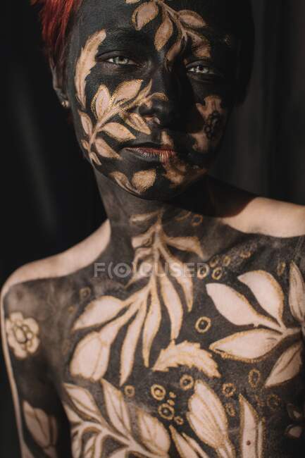 Portrait d'une femme en peinture pour le corps noir et or — Photo de stock