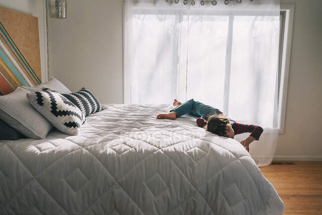 Boy rolling around on bed at home — Stock Photo
