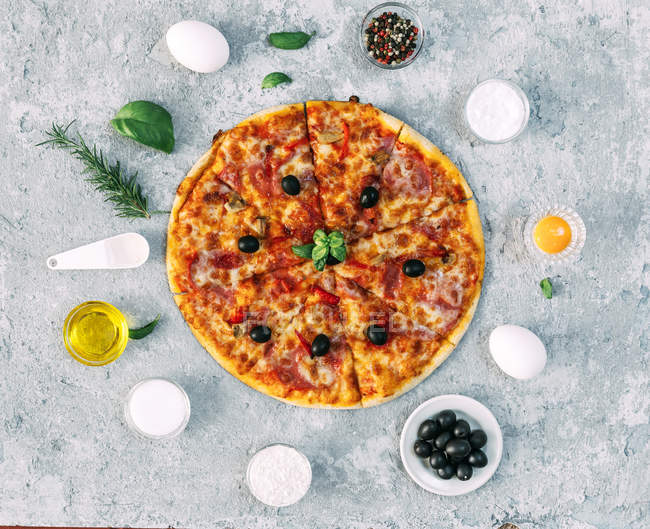 Pizza vegetal rodeada de ingredientes frescos - foto de stock