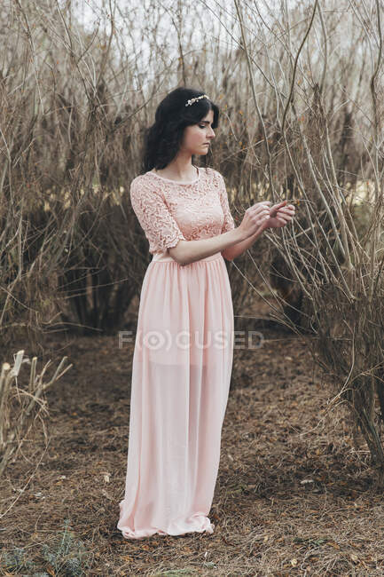 Retrato de una mujer en un vestido largo de pie en el bosque - foto de stock