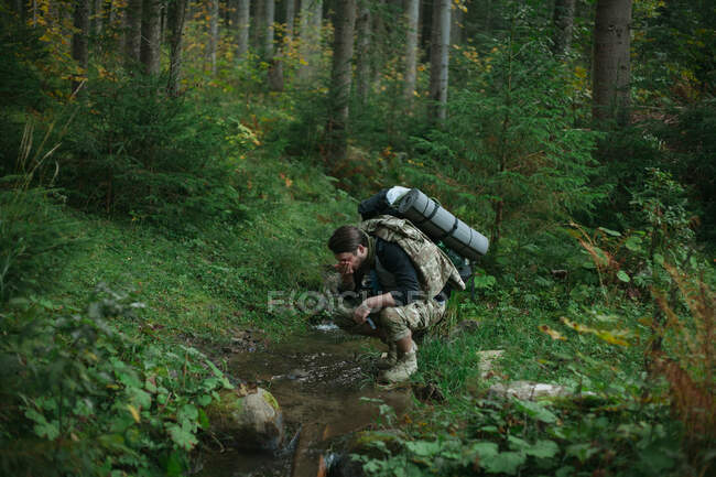Mann trinkt Wasser aus einem Bach, Ukraine — Stockfoto